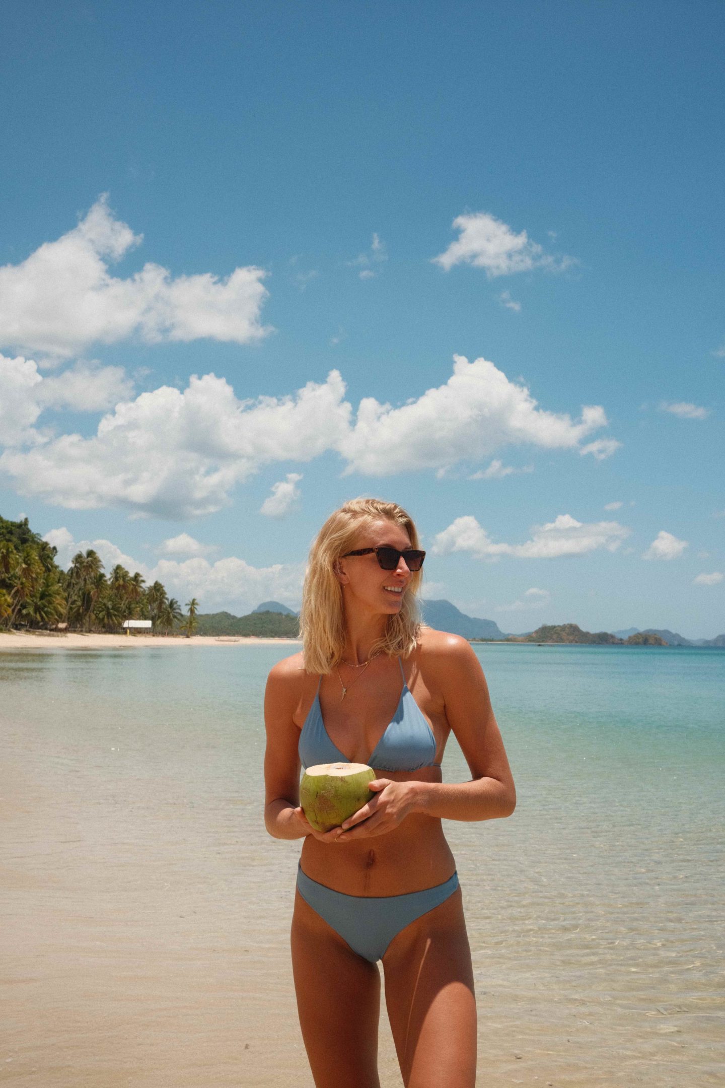 Zanna van Dijk holds a coconut while on a beach in the Philippines